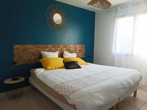 een blauwe slaapkamer met een groot bed met gele kussens bij Aux jardins d'Héloise in Crest