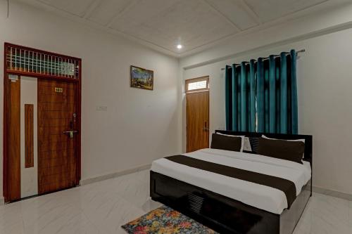 OYO Flagship Hotel Aanandwan Palace في فاراناسي: غرفة نوم بسرير كبير وستارة زرقاء