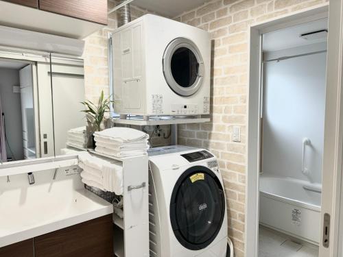 baño con lavadora y secadora de ropa y pared de ladrillo en M&Y Ishigaki Island / 3 Bedroom House, en Nagura