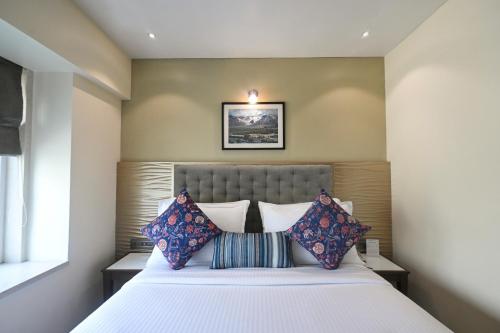 a bedroom with a large white bed with pillows at Hotel Le Grande - Mumbai International Airport in Mumbai