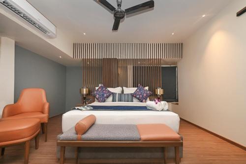 a bedroom with a bed and two orange chairs at Hotel Le Grande - Mumbai International Airport in Mumbai