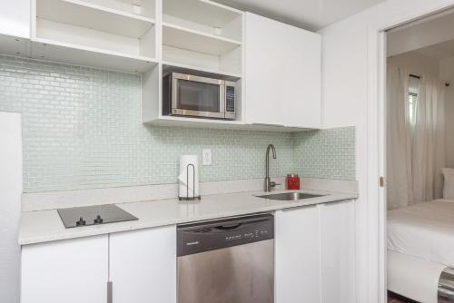 uma cozinha branca com um lavatório e um micro-ondas em Casa Gaby Apartments Part of the Oasis Casita Collection em Miami Beach