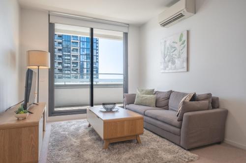 a living room with a couch and a large window at Panoramic Views 2BR with Pool and Free carpark in Melbourne