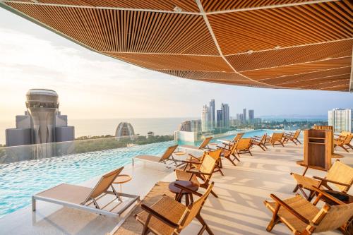 a row of chairs on the roof of a building with a pool at Akara Hotel Pattaya in Pattaya North