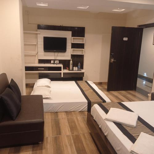 a hotel room with two beds and a television at Hotel Shubh Ashish Near Bank More in Dhanbād