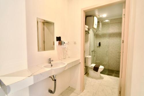 a white bathroom with a sink and a toilet at Gulala Azana Hotel & Resort Guci Tegal in Tegal