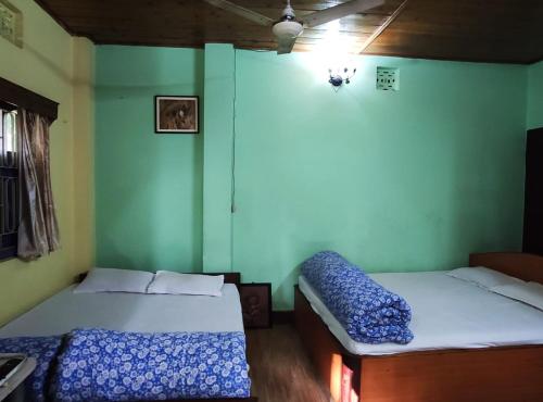 2 camas en una habitación con paredes verdes en Sylvan Retreats, en Lataguri