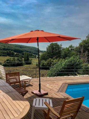un parasol rouge assis sur une terrasse à côté d'une piscine dans l'établissement ✰Chaleureuse Quercynoise avec piscine & jolie vue✰, à Montcuq