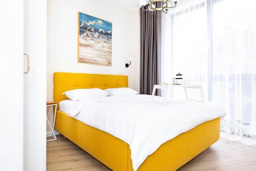 um quarto com uma cama amarela e uma janela em cohost I Sunny, Bright & New Apt w-Balcony @ Renesanso em Vilnius