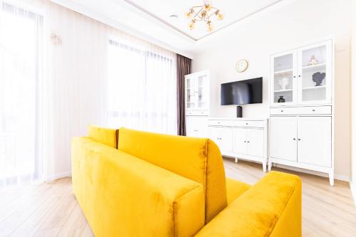 um sofá amarelo numa sala de estar com uma televisão em cohost I Sunny, Bright & New Apt w-Balcony @ Renesanso em Vilnius