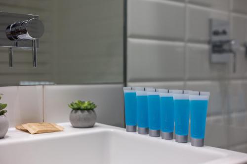 a row of blue glasses sitting on a bathroom sink at Wilanów Branickiego Deluxe Apartment in Warsaw
