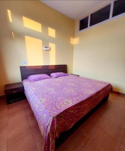 a bedroom with a bed with a purple comforter at Hotel Hill Valley, Ooty in Ooty