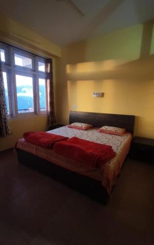 um quarto com uma cama com lençóis vermelhos e uma janela em Hotel Hill Valley, Ooty em Ooty