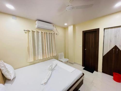 a bedroom with a white bed and a door at Mohor Inn in Kharagpur