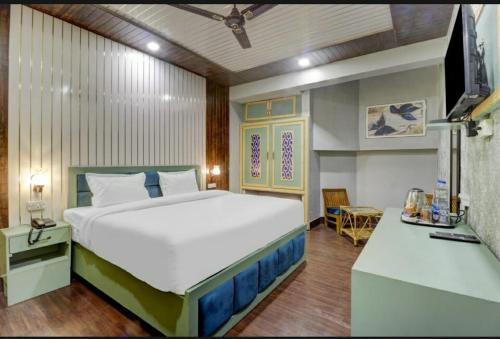 a bedroom with a large bed and a television at Hi hotel By Madras in Rishīkesh