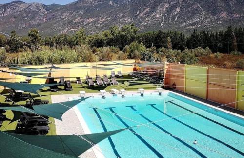 une grande piscine avec des chaises et des montagnes en arrière-plan dans l'établissement HOTEL IL SILLABARIO, à Iglesias