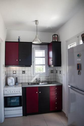 a kitchen with red cabinets and a white refrigerator at Glifada Sea View penthouse in Kastraki Naxou