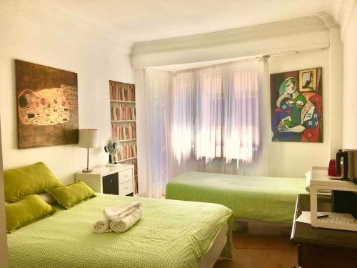 a bedroom with two beds with green sheets at 4 Rooms Playa Surf Cine- Parking y Terraza in Donostia-San Sebastián