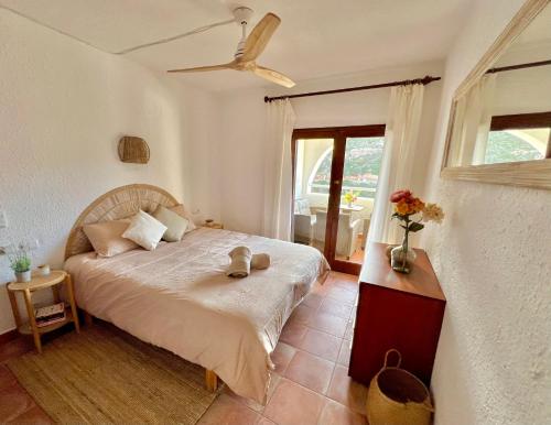 um quarto com uma cama, uma ventoinha e uma janela em Beachfront Apartment in Cala Morell em Cala Morell