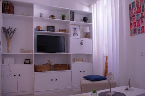 sala de estar con estanterías blancas y TV en Cozy apartment in the heart of the historic center, en Corfú