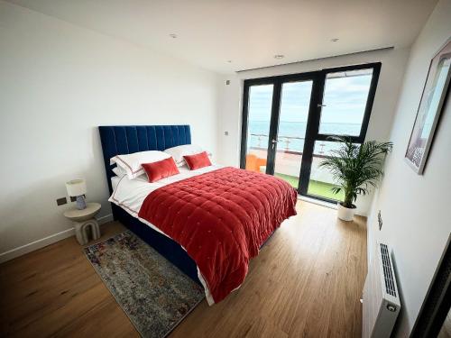 a bedroom with a bed with a red blanket at Stunning beach front apartment with sea views in Ramsgate