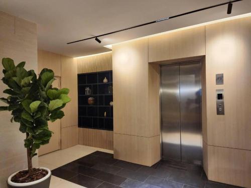 um corredor com um elevador de metal e um vaso de plantas em Lee Nova Hotel em Bangna