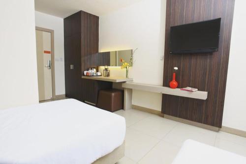 um quarto com uma cama e uma secretária com uma televisão em Lee Nova Hotel em Bangna