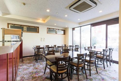 un comedor con mesas, sillas y ventanas en Hotel Bougainvillea Minowa, en Tokio