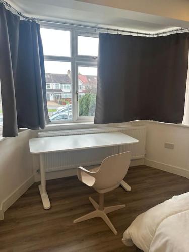 a desk and a chair in a room with a window at Delightful studio room in house in Raynes Park