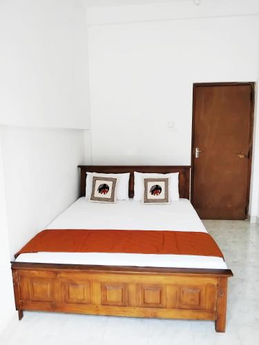康提的住宿－Kandy Wellington Homestay，一间卧室配有一张带两个枕头的木床