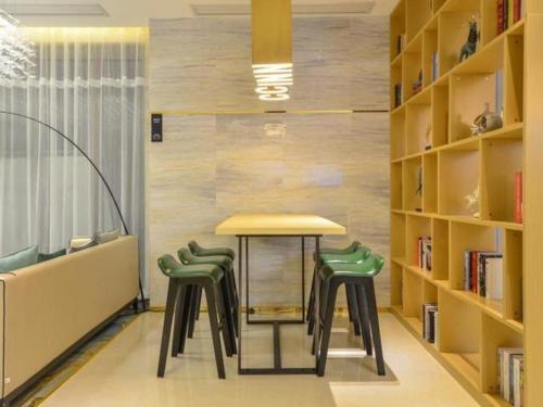 Jiang'anにあるCity Comfort Inn Wuhan Yuanlin Road Metro Stationの図書室(テーブルと緑の椅子2脚付)