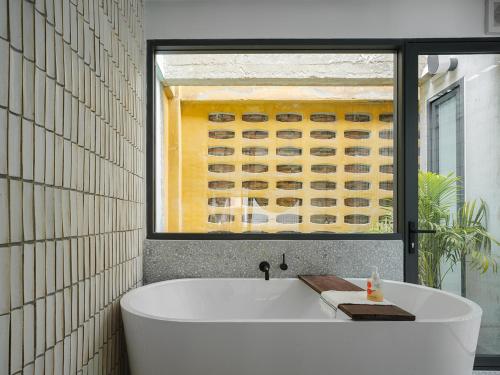 a bath tub in a bathroom with a painting at Stupid Stay in Bangkok