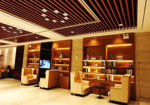 a library with chairs and bookshelves and a tv at JTOUR Inn Wuxi Railway Station Shangmadun Metro Station in Wuxi