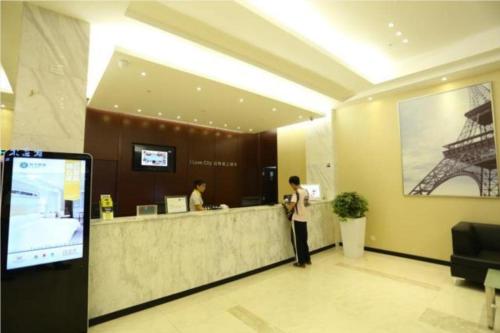 a lobby with two people standing at a counter at City Comfort Inn Guangzhou Zhongluotan Culture Square in Guangzhou