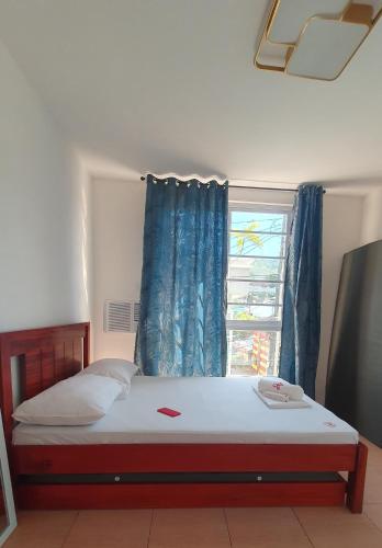 DRA Guesthouse في Romblon: غرفة نوم بسرير وستارة زرقاء ونافذة