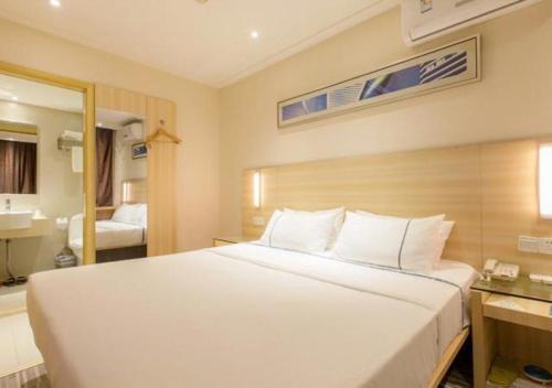 um quarto com uma grande cama branca e uma casa de banho em City Comfort Inn Wuhan Jiefang Avenue Xinrong Light Rail Station em Jiang'an