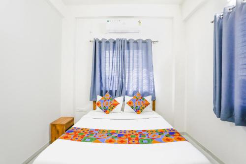 a small bedroom with a bed with blue curtains at FabHotel Blue Ocean MNJ Resort in Nashik