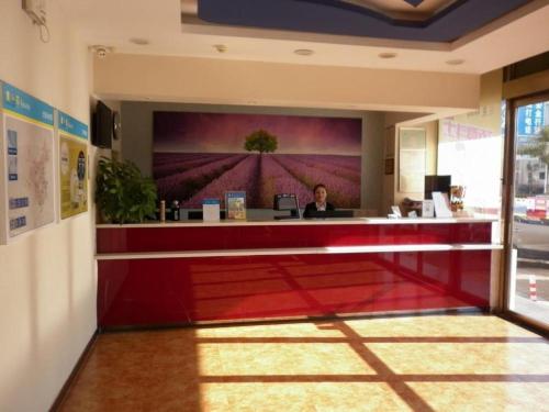 a woman sitting at a reception desk in a lobby at 7 Days Inn Tianjin Development Zone Fifth Street Convention Center in Binhai