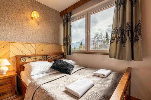 ein Schlafzimmer mit einem Bett mit zwei Kissen und einem Fenster in der Unterkunft Apartamenty pod Słońcem in Kościelisko