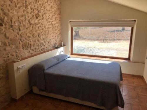 1 dormitorio con cama y ventana grande en Casita rural entre olivos, en Biar
