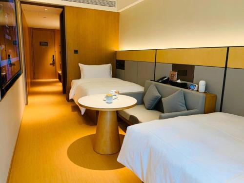 ein Hotelzimmer mit 2 Betten, einem Tisch und einem Sofa in der Unterkunft JI Hotel Hangzhou Qianjiang New City Civil Center in Hangzhou