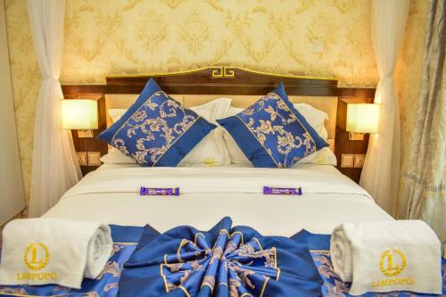 a bed with blue and white pillows and towels at Limpopo Suites in Nairobi