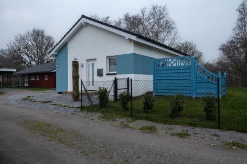 uma casa branca e azul com uma cerca em frente em Ferienhaus Möwennest em Sehestedt