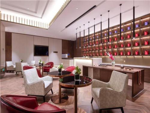 un vestíbulo de hotel con sillas y mesas y una pared de estanterías en E-Cheng Hotel Changchun Yiqi West High-Speed Railway Station, en Changchún