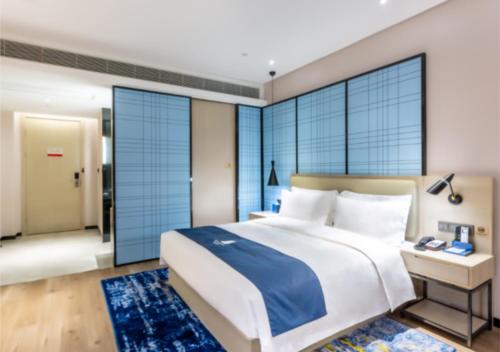 a bedroom with a large bed and large windows at Echarm Hotel Jiaxing Xiuhu Park Government Center in Jiaxing