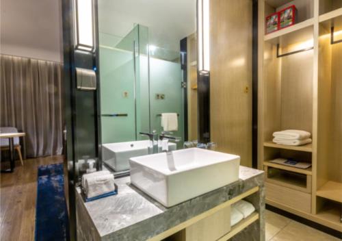 a bathroom with a sink and a large mirror at Echarm Hotel Jiaxing Xiuhu Park Government Center in Jiaxing