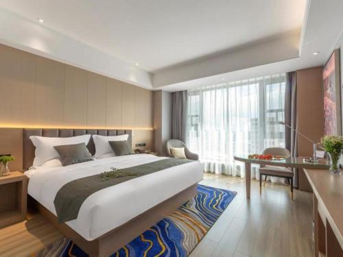 a hotel room with a large bed and a desk at Gya Hotel Kunming Zijin Center Xiaodongcun Metro Station in Kunming