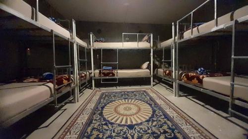 a room with three bunk beds and a rug on the floor at Neena S Hostel in Ban Nua