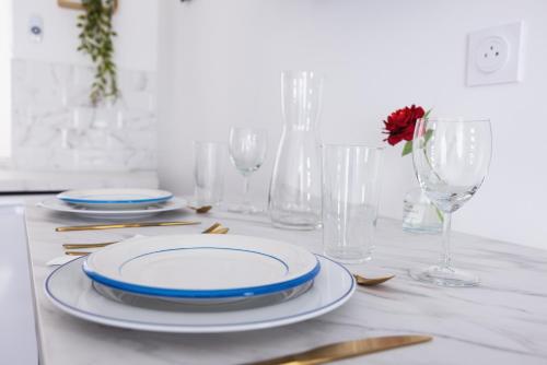 a table with plates and glasses and a red flower at Le Requiem -Terrasse -Climatisation -Gare in Montluçon