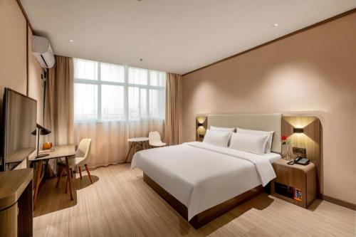 a bedroom with a large white bed and a desk at Hanting Hotel Guangzhou North Railway Station in Huadu
